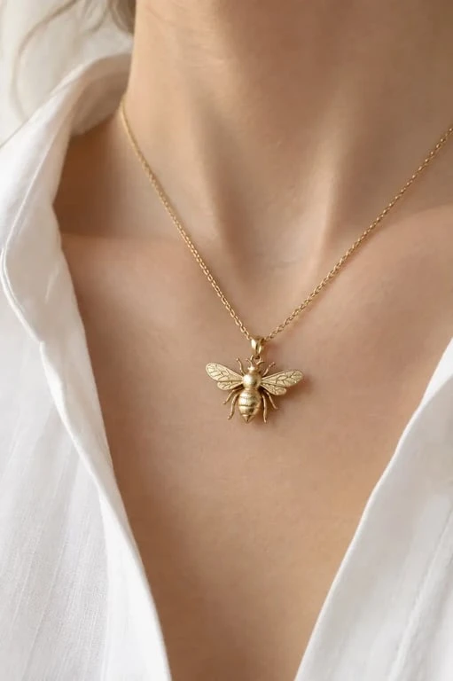 Bijou abeille pendentif en or porté au quotidien sur une chemise blanche