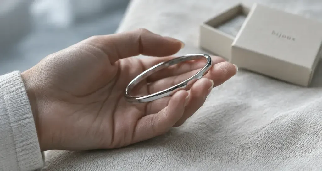 Le jonc bijoux structure le poignet avec élégance, sans alourdir la tenue