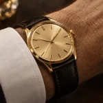 Montres homme en or au poignet, bracelet cuir noir et cadran doré